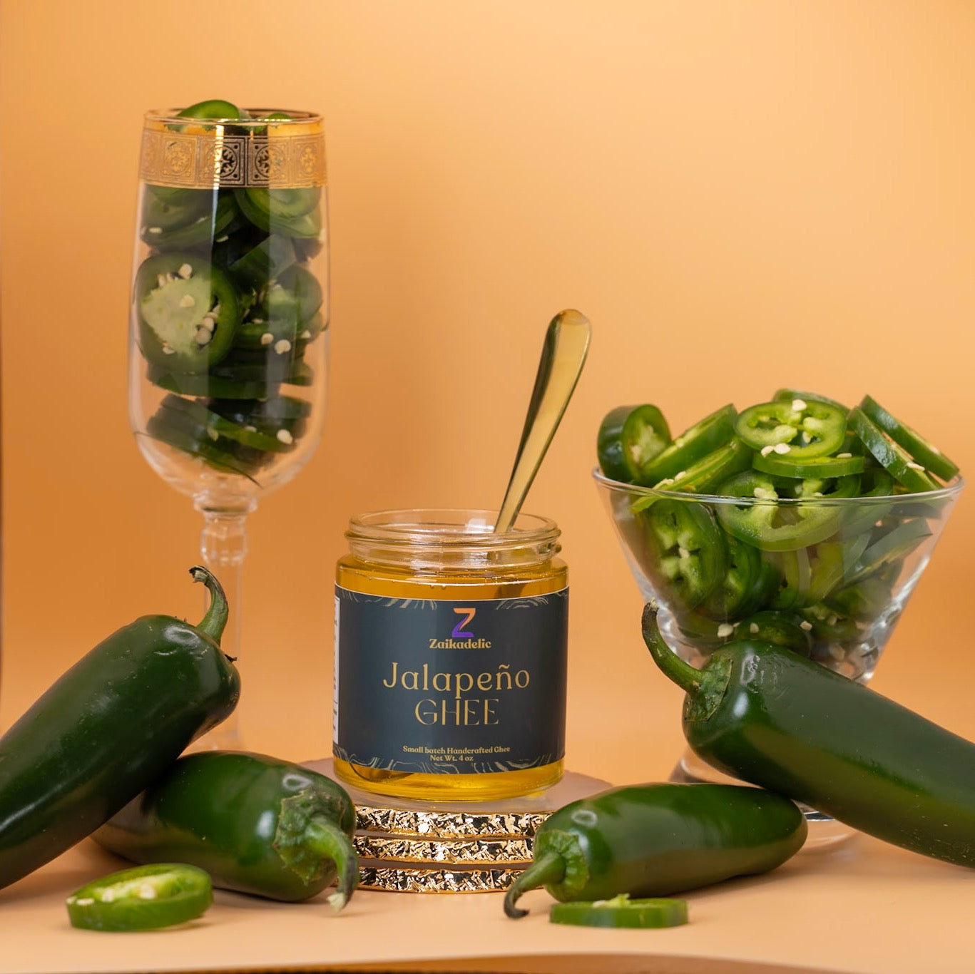 A jar of Zaikadelic Jalapeño Ghee surrounded by fresh jalapeños